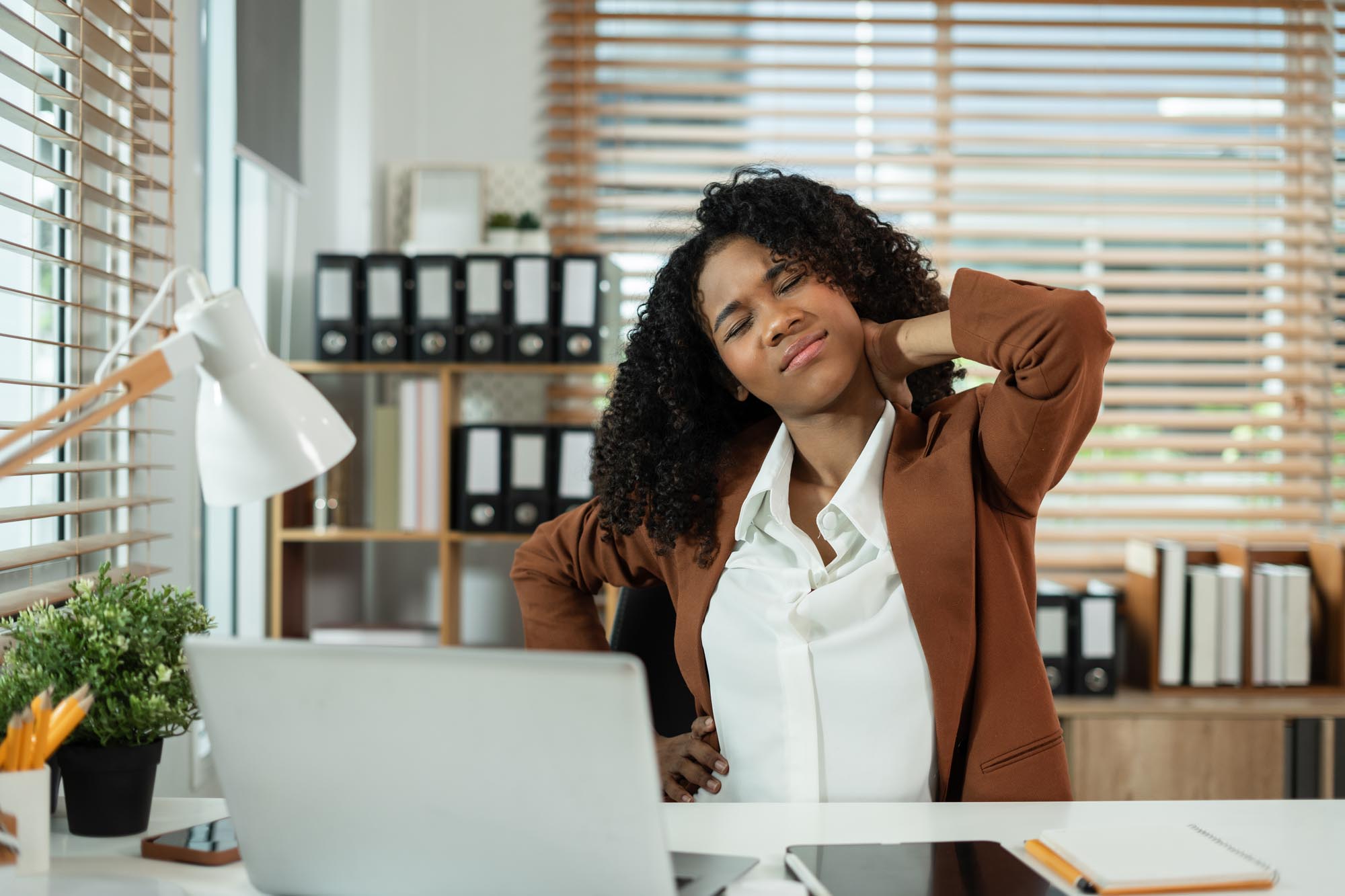 Businesswoman is doing a stretchy posture due to sitting in the office for too long, office syndrome concept.