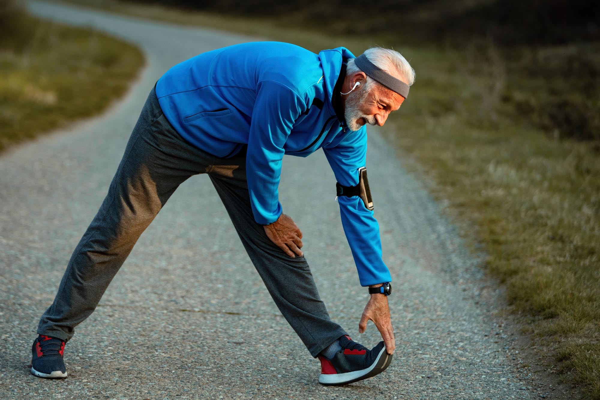 Active senior athlete doing stretching exercises in nature.